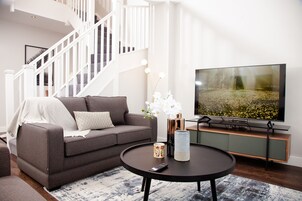 Una sala de estar moderna con un sofá gris, una mesa de centro redonda y un televisor de pantalla plana.