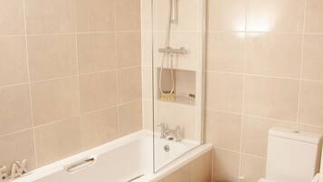 A modern bathroom with a bathtub, toilet, and shower.