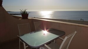Ein Balkon mit Tisch und Stühlen mit Blick auf einen Strand.