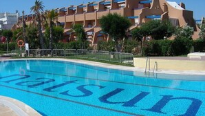 Ein Pool mit dem Schriftzug 'Matsun' auf der Wasseroberfläche, umgeben von einer Poollandschaft mit Metallgeländer und Palmen.