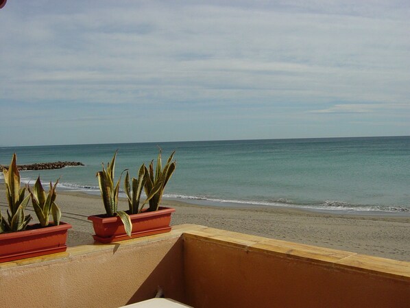 A balcony with a view of the beach and the ocean.