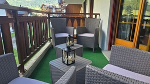 Un balcon agrémenté de meubles en osier, d’une petite table et d’une lanterne.