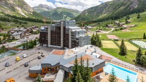 A hotel with a modern architectural style, featuring a central building with multiple floors and a swimming pool. - South studio ski-in/ski-out in Val-d'Isère, pets allowed (Val-d'Isère)