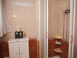 Une salle de bain avec douche, un meuble-lavabo équipé d’une radio et des objets de décoration.