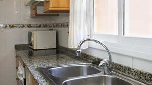 A kitchen with two stainless steel sinks, a granite countertop, and wooden cabinets.