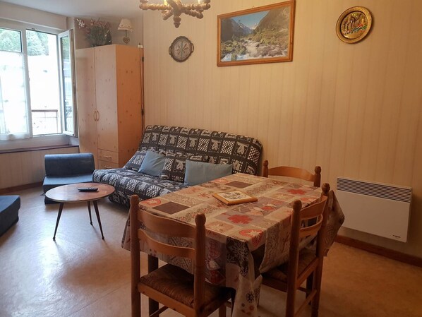 A cozy living room with a patterned sofa, a small round table, and a dining table with chairs. - Apartment 4 People Center Cauterets (Cauterets)