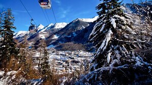 A ski lift chair ascending a snowy mountain with a town below. - Apartment 4 People Center Cauterets (Cauterets)