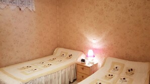 A bedroom with two single beds, a nightstand with a lamp, and floral-patterned wallpaper. - Apartment 4 People Center Cauterets (Cauterets)