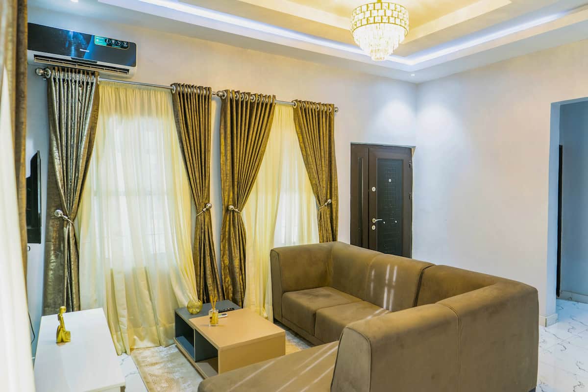 A living room with a sofa, curtains, a door, and a chandelier.