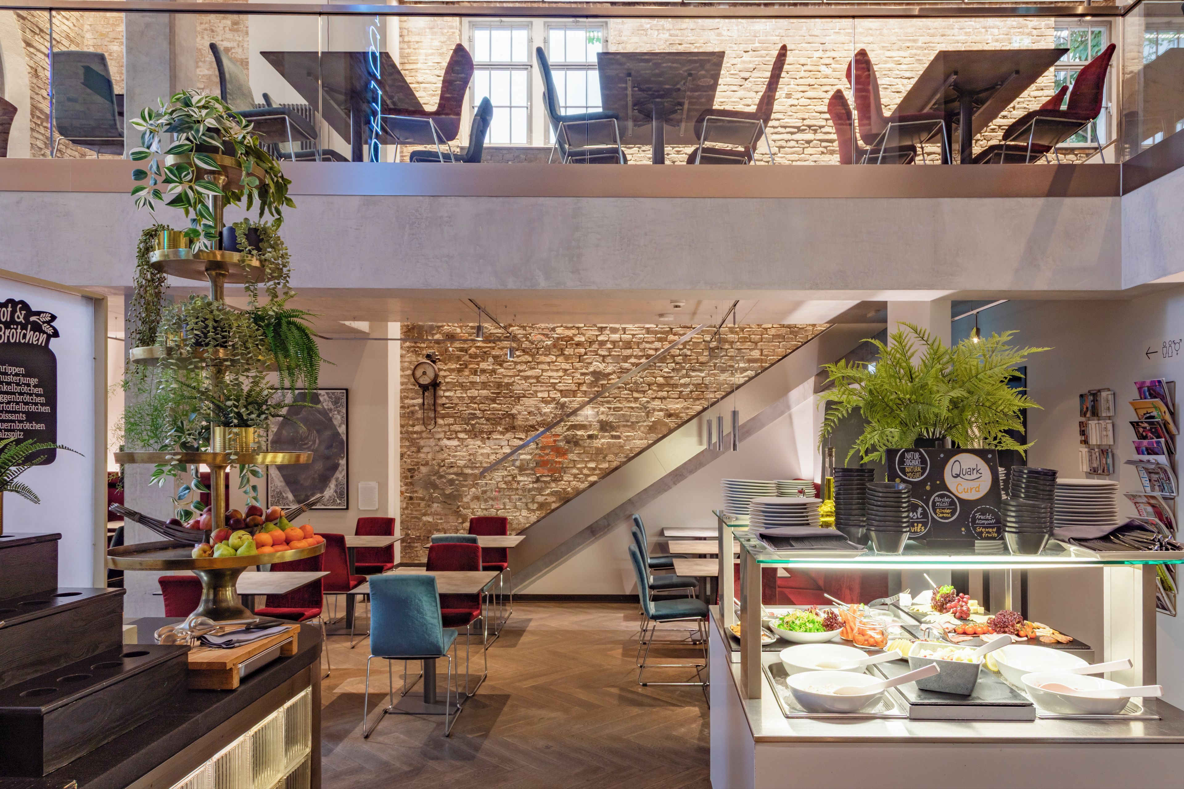 Ein modernes Restaurant mit Steinwand, Holzböden und verschiedenen Sitzgelegenheiten, darunter Tische und Stühle.