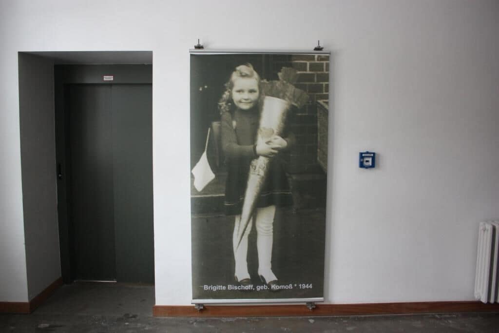 Ein Flur mit einer Tür links und einem Poster rechts.