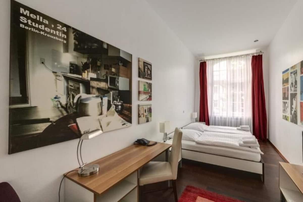 Un dormitorio pequeño y moderno con cama, escritorio y televisor.