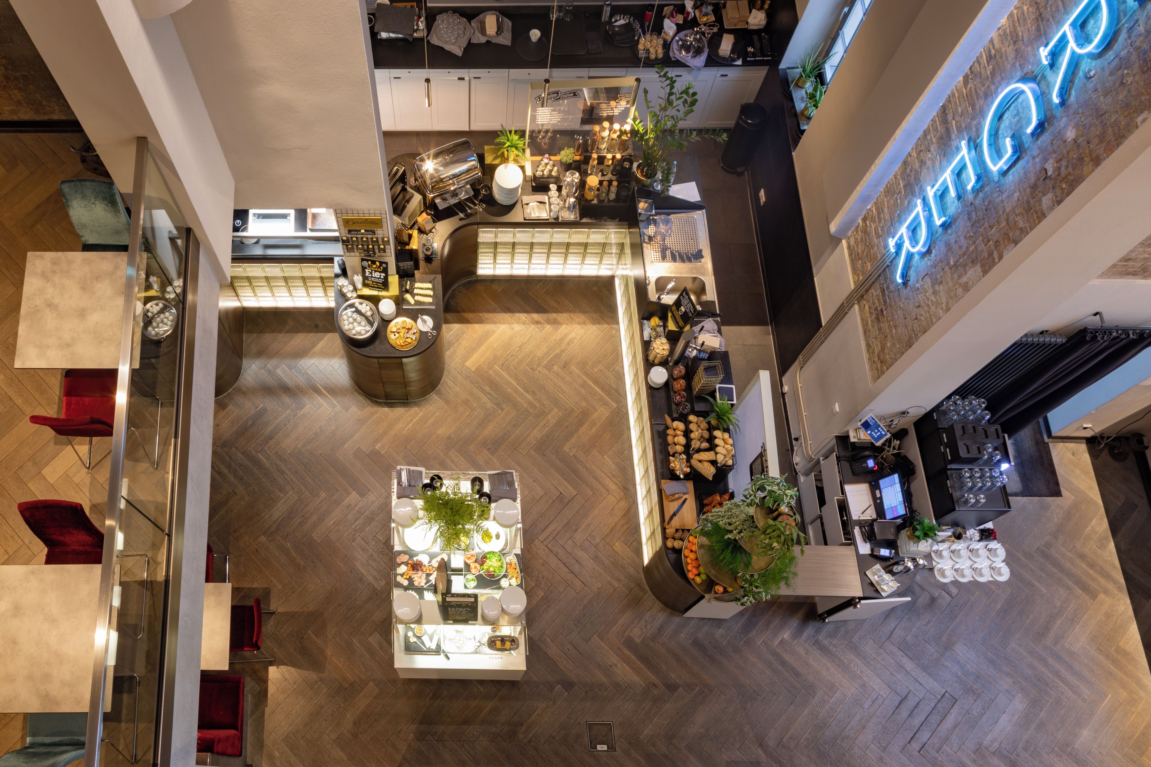 Ein Restaurant mit hohen Decken und offener Gestaltung, das eine zentrale Essbereich, eine Bar und eine Theke mit einer Neonreklame bietet.