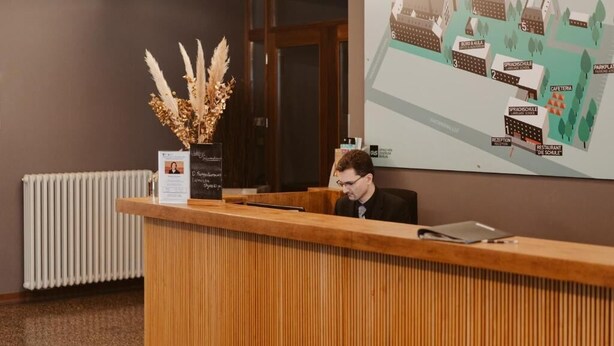 A reception desk with a wooden finish, a potted plant, and a map on the wall.