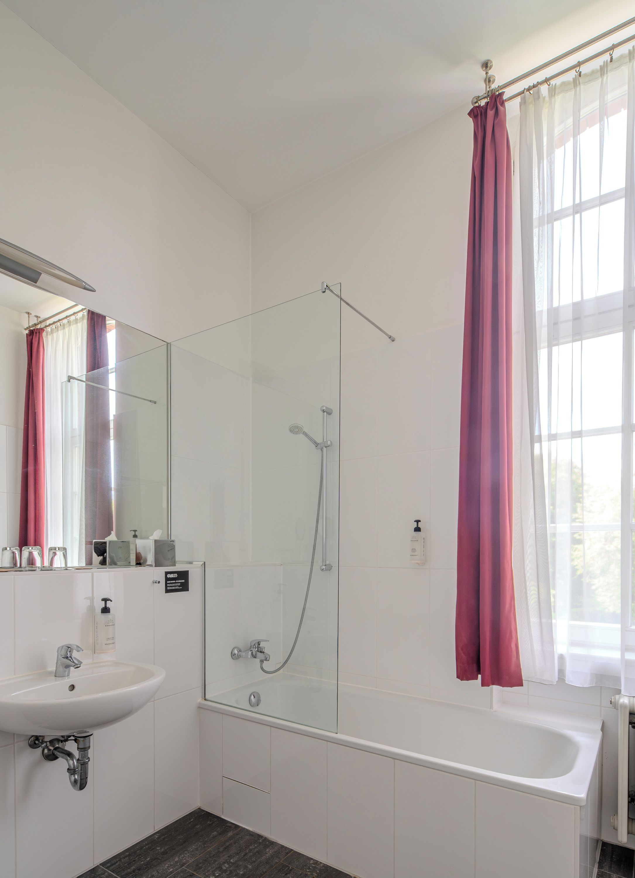 Un baño moderno con ducha envuelta en cristal, un lavabo blanco y una bañera.