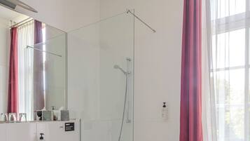 Un baño moderno con ducha envuelta en cristal, un lavabo blanco y una bañera.