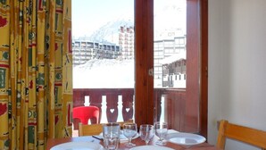 Mesa lista para cuatro personas con vista a una montaña nevada y edificios al fondo.