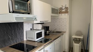 Une cuisine compacte équipée d’un four encastré, d’un micro-ondes, d’un grille-pain et d’un lave-vaisselle.