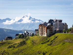 A mountain resort with chalet-style buildings, a ski lift, and a view of snow-capped peaks. - Charming Ski-in/Ski-out Apt with Balcony, Sleeps 6, Access to Spassio Spa, Close to Amenities (Peyragudes)
