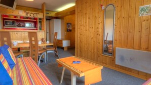 Une pièce chaleureuse avec un mur en bois, une petite table, un canapé et un téléviseur.