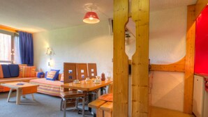 Une pièce chaleureuse avec une table en bois, des chaises, un canapé et un buffet rouge.
