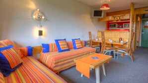 Une pièce confortable avec un canapé, une petite table et un coin cuisine.