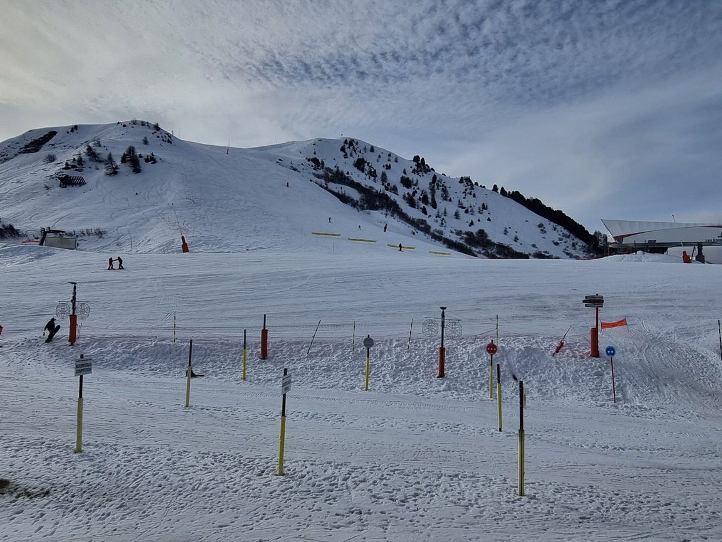 A snow-covered ski slope with marked trails and safety barriers.