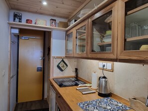 A compact kitchen with wooden cabinets, a countertop, and a small sink.