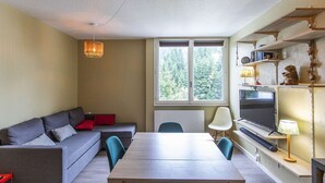 Uma sala de estar moderna com sofá, mesa de jantar e televisão.
