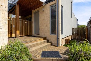 Una casa moderna con una terrazza in legno, una porta e una finestra.