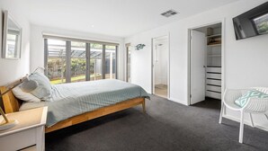 A bedroom with a bed, a desk, a chair, a wardrobe, and a television.