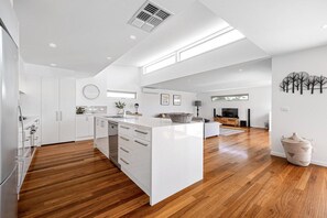 Cucina spaziosa con isola centrale, pavimento in legno e mobili bianchi.
