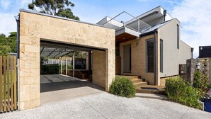 A modern house with a garage, stone facade, and a covered outdoor area.