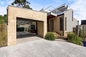 Una casa moderna amb garatge, façana de pedra i zona exterior coberta.