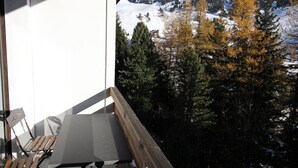 A balcony with a table and chairs, overlooking a snowy mountain and trees. - Renovated well-equipped studio, south exposure, Chamrousse (Chamrousse)