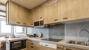 A compact kitchen with wooden cabinets, a built-in microwave, a stove, and a sink.