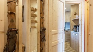 A wooden interior with a kitchen area visible through an open door.