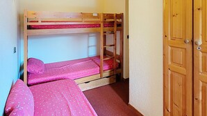 Habitación con literas, una puerta de madera y un interruptor de luz en la pared.