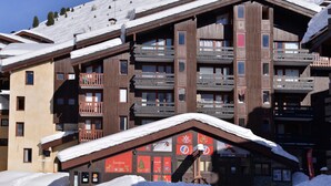 Un edificio de madera de varios pisos con balcones, un telesilla y un letrero para un restaurante llamado "Garderie".