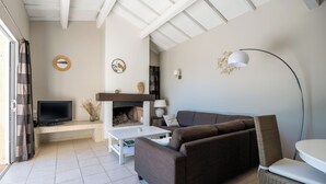 A living room with a sofa, TV, fireplace, and a dining area with a table and chair. - Enjoy the peace and serenity of mountain walks. (Cruis)