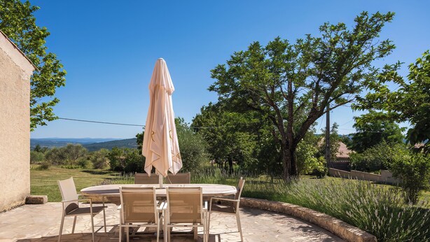 A patio with a round table and chairs, an umbrella, and a view of the countryside. - Enjoy the peace and serenity of mountain walks. (Cruis)