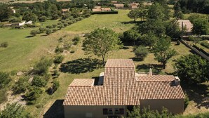 A rural house with a tiled roof, surrounded by green fields and trees, with a view of distant hills. - Enjoy the peace and serenity of mountain walks. (Cruis)