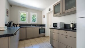A modern kitchen with a black countertop, stainless steel appliances, and beige cabinetry. - Enjoy the peace and serenity of mountain walks. (Cruis)