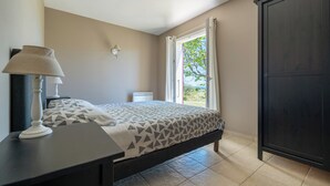 A bedroom with a bed, a bedside table with a lamp, a wardrobe, and a window with curtains. - Enjoy the peace and serenity of mountain walks. (Cruis)