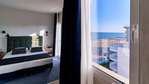 Ein Schlafzimmer mit einem großen Bett, Meerblick und einem Balkon mit Geländer.
