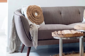 A grey sofa with a woven throw pillow, a white pillow, and a grey throw blanket.
