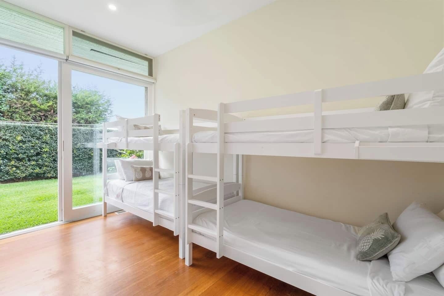 A bunk bed room with a sliding glass door leading to a garden.