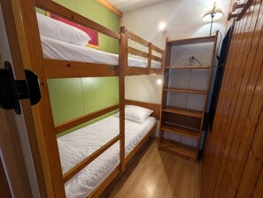 Habitación con literas, una pared verde y una estantería de madera.