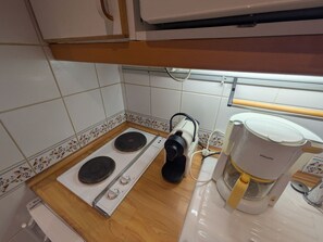 Una cocina con estufa, cafetera y una ventana sobre la encimera.