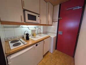 A compact kitchen with a microwave, coffee maker, sink, and dishwasher.